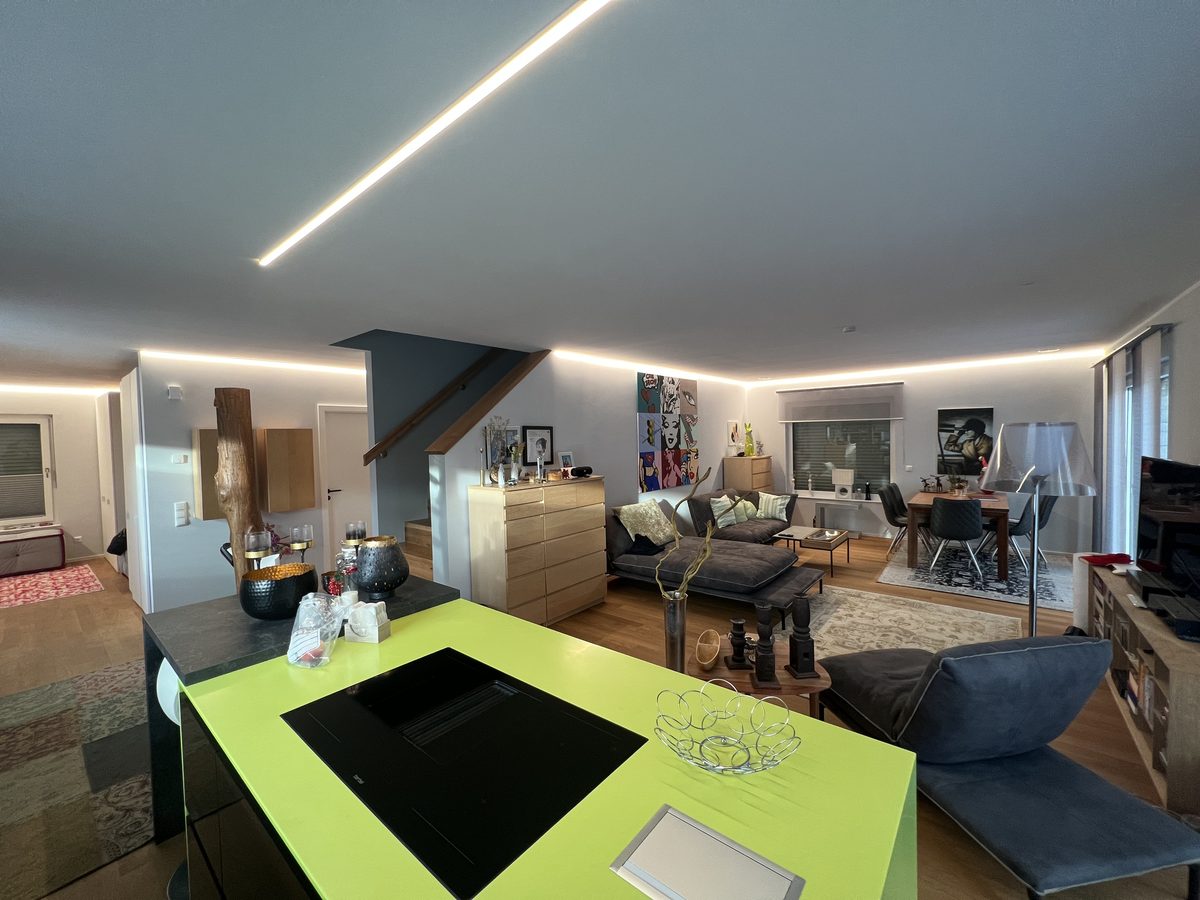 Offener Wohnraum mit Kochinsel und Lichtlinien in der Decke