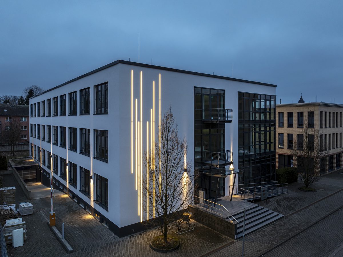 Bürogebäude bei Dämmerung mit senkrechten Lichtlinien an der Fassade