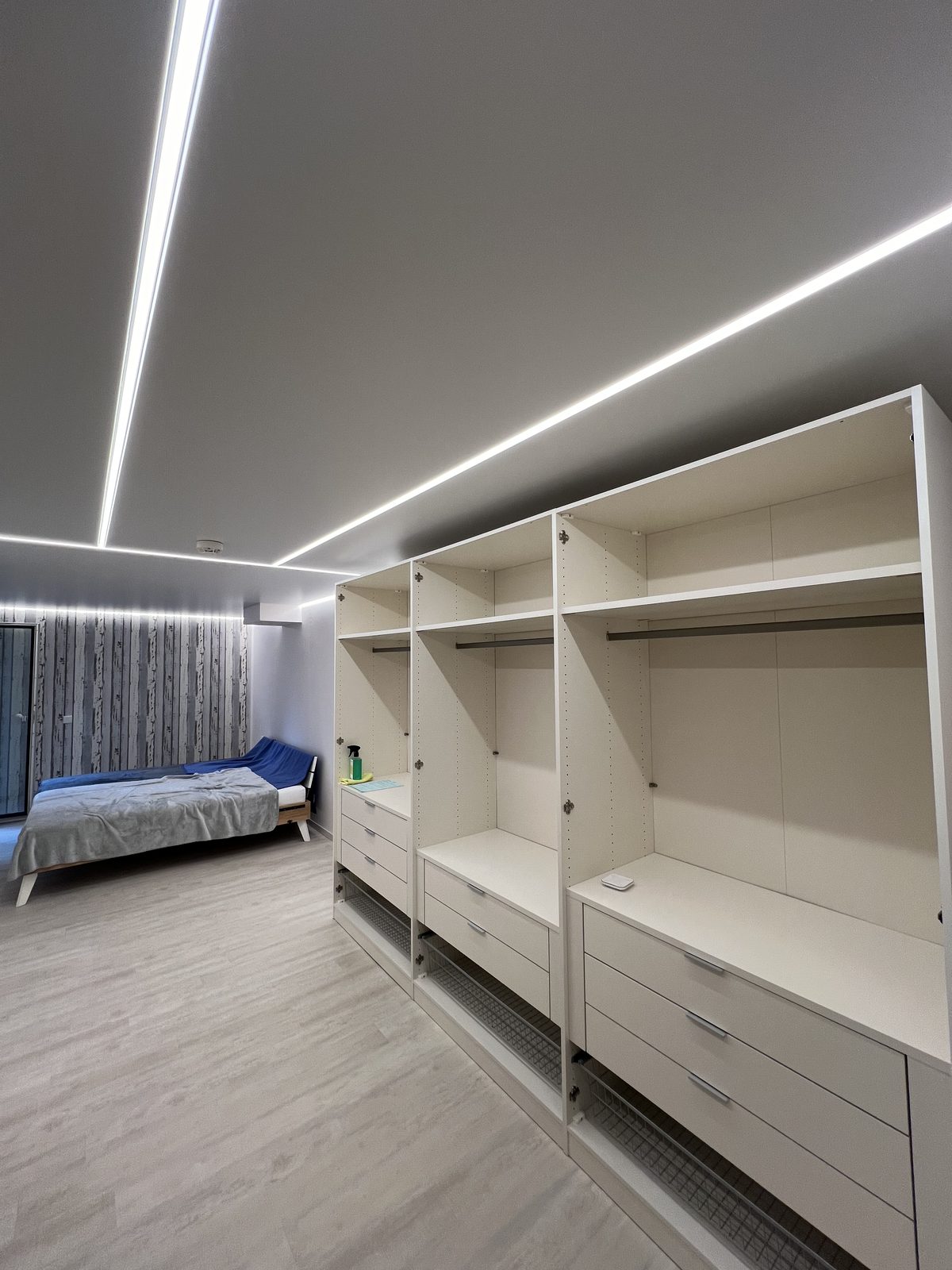 Schlafzimmer mit Spanndecke und zwei parallelen Lichtlinien über dem Kleiderschrank