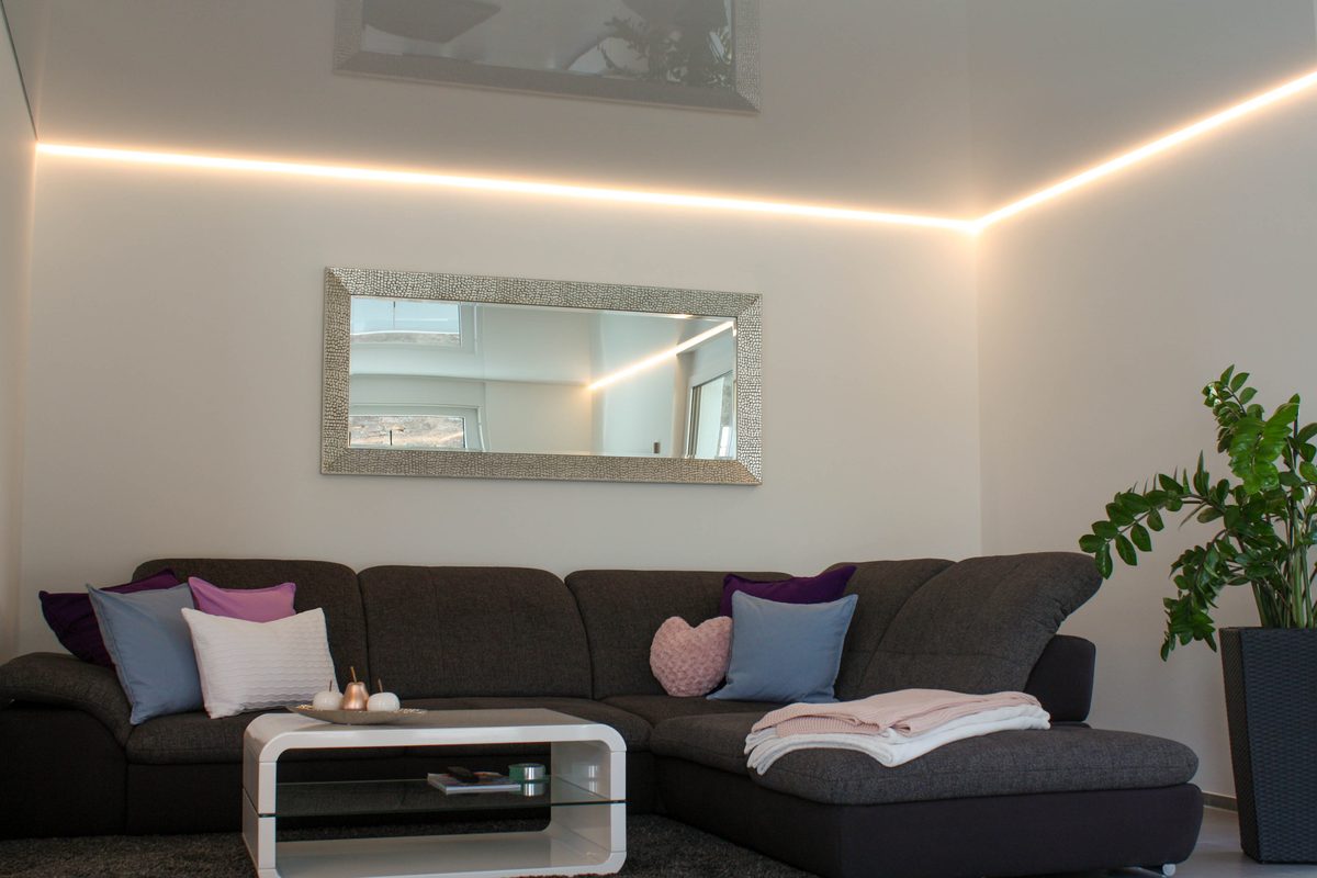 Wohnzimmer mit Hochglanz-Spanndecke und Lichtlinie über der Sofaecke