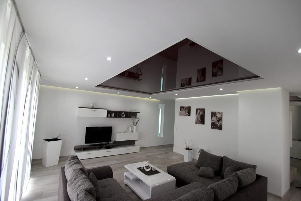 Wohnzimmer mit schwarzem Hochglanzfeld in der Spanndecke und indirekter Beleuchtung